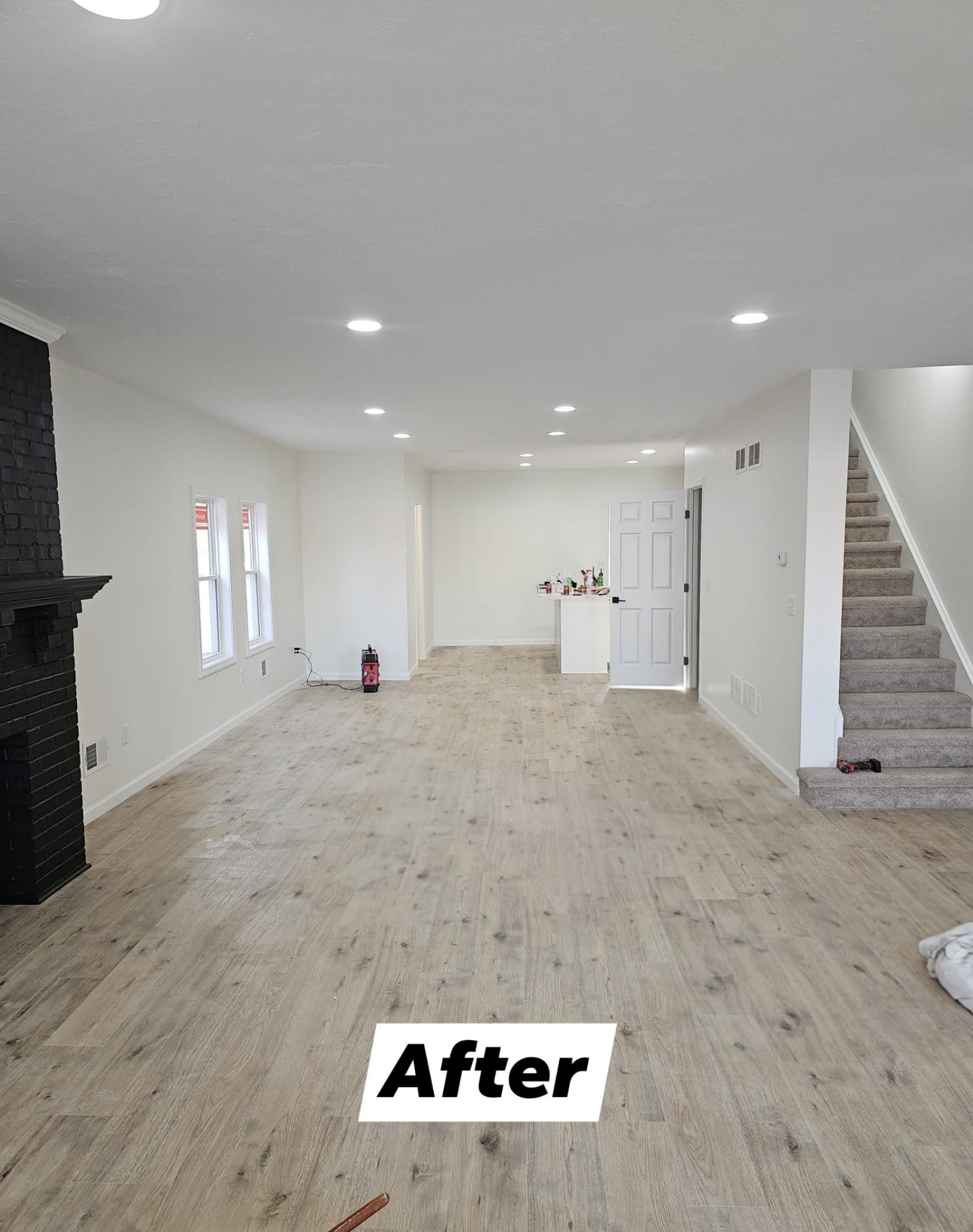 Same room finished with smooth painted drywall, recessed lighting, and new wood-look flooring